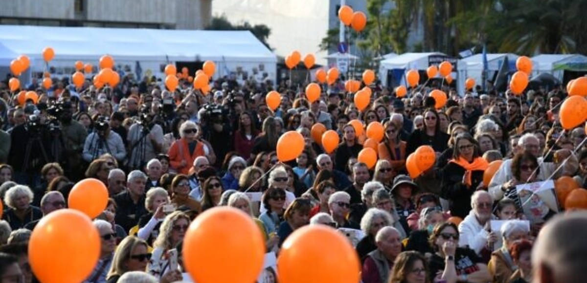 Des centaines de personnes brandissant des ballons orange marquent le premier anniversaire de l'otage Kfir Bibas à Tel Aviv